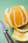 Очищений апельсин з ножем — стокове фото