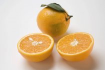 Oranges entières et coupées en deux — Photo de stock