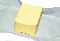 Closeup view of a butter block on paper — Stock Photo
