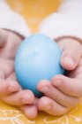 Closeup view of child hands holding a blue egg — Stock Photo