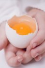 Manos de niño sosteniendo huevo crudo - foto de stock