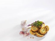 Vista elevata di rotoli di aglio con erbe sulla superficie bianca — Foto stock