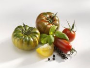 Tomatoes with basil and bunch of peppercorns — Stock Photo