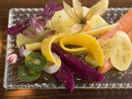 Vue rapprochée de salade de fruits exotiques sur plaque de verre — Photo de stock