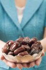 Woman holding dish of dates — Stock Photo