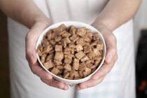 Closeup view of hands holding a bowl of breakfast cereal — Stock Photo