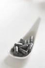 Vue rapprochée de capsules de charbon sur une cuillère en porcelaine — Photo de stock