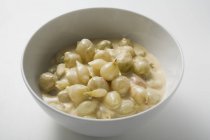 Перлова цибуля в вершковому соусі на білій тарілці — стокове фото