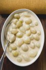 Cipolle di perla in salsa alla panna in piatto con cucchiaio — Foto stock