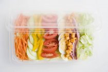 Mixed salad with ham and egg in a plastic tray on white surface — Stock Photo