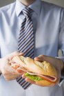 Empresário segurando sanduíche de presunto — Fotografia de Stock