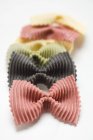 Pasta farfalle coloreada en fila - foto de stock