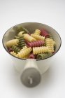 Vue rapprochée des pâtes Riccioli colorées dans une passoire métallique — Photo de stock