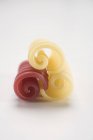 Closeup view of red and yellow Riccioli pasta on white surface — Stock Photo