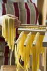 Woman hanging ribbon pasta on sticks — Stock Photo
