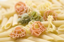 Coloured animal-shaped pasta and penne — Stock Photo