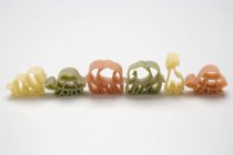 Pastas coloreadas en forma de animal en fila - foto de stock