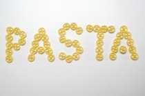 Word Pasta of wheel pasta pieces — Stock Photo