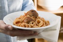 Woman holding Spaghetti with meatballs — Stock Photo