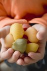 Kind hält bunte Lumaconi-Nudeln in der Hand — Stockfoto