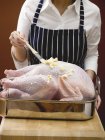 Woman brushing turkey with butter — Stock Photo