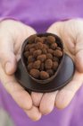 Closeup cropped view of hands holding chocolate egg half filled with truffles — Stock Photo