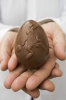 Closeup cropped view of hands holding chocolate egg — Stock Photo