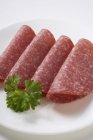 Vier Scheiben Salami mit Petersilie — Stockfoto