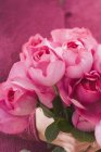 Vue rapprochée des mains tenant un bouquet de roses roses — Photo de stock