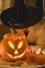 Woman in witch hat holding pumpkin lantern — Stock Photo