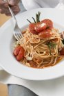 Жінка їсть спагеті з помідорами — стокове фото