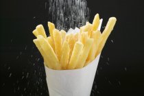 Espolvorear sal sobre papas fritas - foto de stock