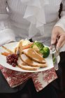 Cropped view of woman serving turkey breast with vegetables — Stock Photo