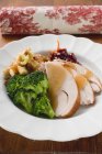 Грудь индейки с брокколи, начинкой хлеба и клюквой на белой тарелке — стоковое фото
