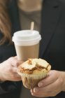 Mulher segurando muffin e xícara de café — Fotografia de Stock