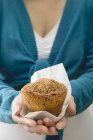 Mulher segurando muffin em guardanapo de papel — Fotografia de Stock