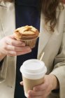Donna che tiene muffin e tazza di caffè — Foto stock