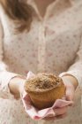 Mulher segurando muffin no guardanapo verificado — Fotografia de Stock