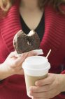 Mujer sosteniendo rosquilla y taza de café - foto de stock