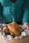 Woman holding whole roasted chicken — Stock Photo