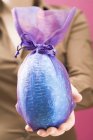 Крупним планом обрізаний вид жінки, що тримає великий шоколад Великоднє яйце — стокове фото