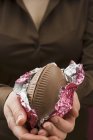 Vue rapprochée de la femme tenant un oeuf en chocolat coupé en deux dans une pellicule d'aluminium — Photo de stock
