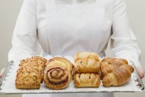 Cropped view of woman holding pastries on silver tray — Stock Photo
