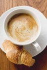 Croissant avec une tasse de cappuccino — Photo de stock