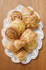 Top view of assorted Danish pastries on lace napkin and wooden surface — Stock Photo