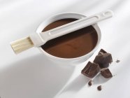 Closeup view of milk couverture with brush and pieces of chocolate — Stock Photo