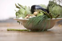 Tigela de legumes: alcachofras, beringelas, cebolinha etc. em placa branca — Fotografia de Stock