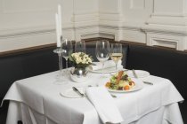 Closeup view of salad and white wine on laid table in restaurant — Stock Photo