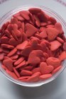 Closeup top view of red sugar hearts in glass bowl — Stock Photo