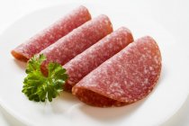 Cuatro rebanadas de salami con perejil - foto de stock